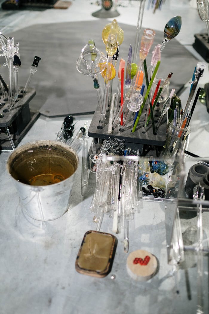 A variety of colorful glassblowing tools and accessories on a workshop tabletop, showcasing the craft of glass art.